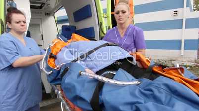 Emergency medical ambulance service paramedics crew fixing senior patient on stretcher