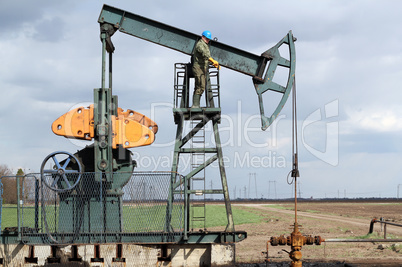 oil and fuel industry oil worker standing on the pump jack
