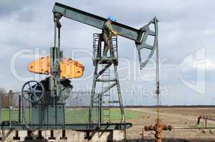 oil and fuel industry oil worker standing on the pump jack