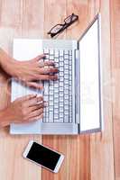 Overhead of female hands typing on laptop