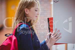 Pretty student with backpack putting notebook in the locker