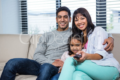 Smiling family watching tv on the sofa