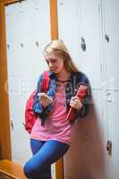 Smiling student leaning against the locker using smartphone
