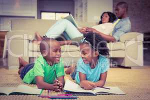 Happy siblings on the floor drawing