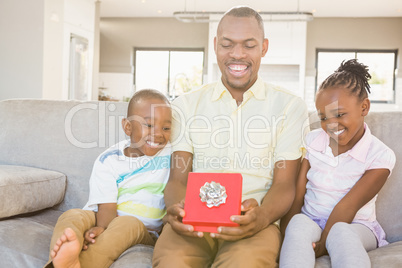 Happy father getting a gift by his son and his daughter