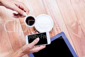 Businesswoman holding smartphone and coffee cup