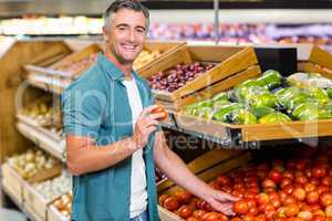 Smiling man choosing a tomato