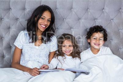 Happy family reading book on the bed