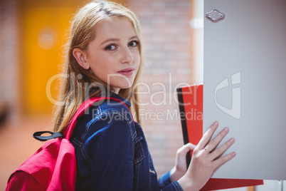 Pretty student with backpack putting notebook in the locker