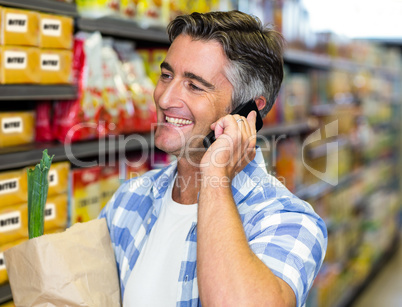 Smiling man on a phone call with grocery bag