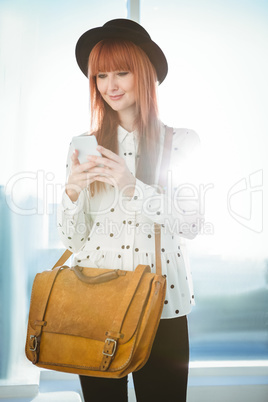 Smiling hipster woman texting with her smartphone