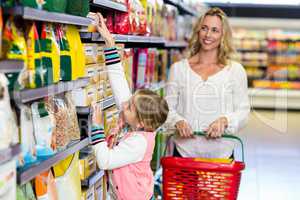 Cute daughter taking food from shelf