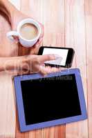 Businesswoman holding smartphone and coffee cup