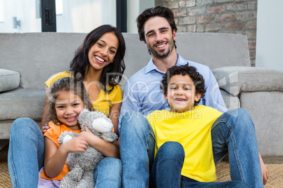 Smiling family sitting on carpet in living room