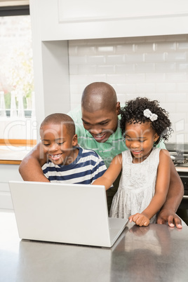 Father using laptop with his children in kitchen