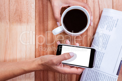 Part of hands holding coffee and smartphone