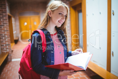 Pretty student with backpack holding notebook looking at the cam