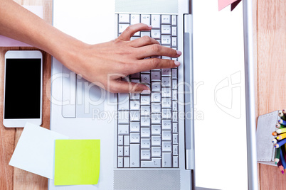 Overhead of feminine hand typing on laptop