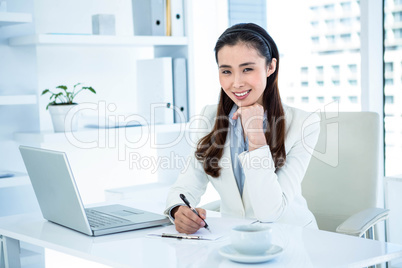 Smiling businesswoman writing on clipboard
