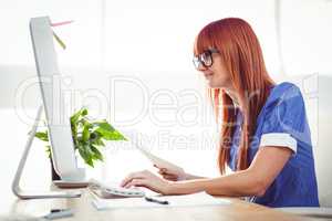 Attractive hipster woman with document typing on keyboard