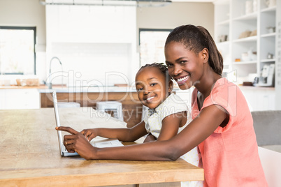 Cute daughter using laptop at desk with mother