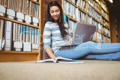 Smiling student sitting on the floor against wall in library stu