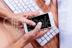 Businesswoman using her smartphone on desk