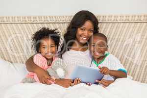 Happy family using tablet in bed