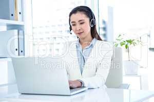 Smiling businesswoman with headset using laptop