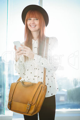 Smiling hipster woman texting with her smartphone