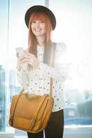 Smiling hipster woman texting with her smartphone