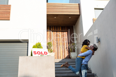 Happy couple hugging in front of new house