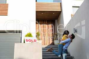 Happy couple hugging in front of new house