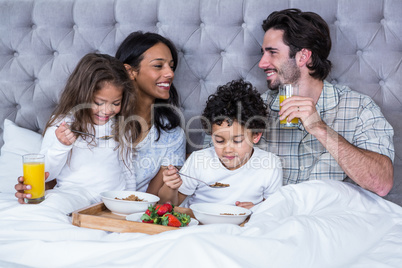 Happy family having breakfast on bed