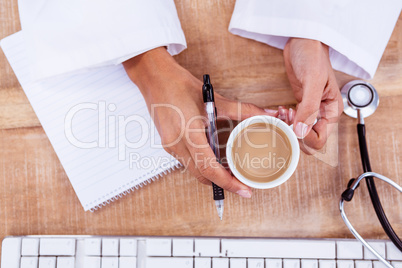 Doctor holding pen and hot beverage