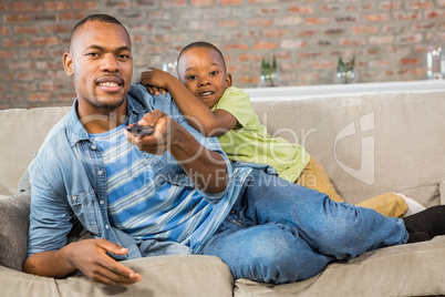 Father and son watching tv together on the couch