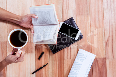 Overhead of feminine hands holding a book and coffee