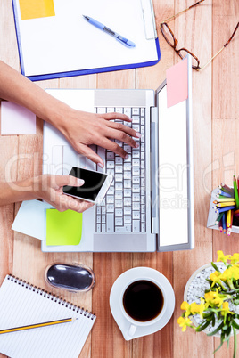 Overhead of feminine hands using laptop and smartphone