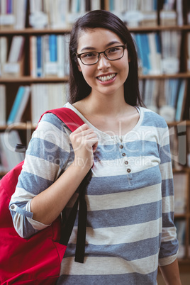 Smiling student with backpack standing in library