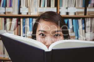 Pretty student hiding face behind a book