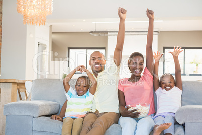 Happy family watching television eating popcorn