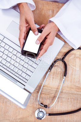 Doctor using smartphone on wooden desk