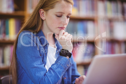Student with smartwatch using laptop in library