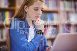 Student with smartwatch using laptop in library