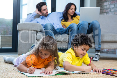 Children laying on the carpet drawing in living room