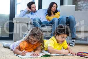 Children laying on the carpet drawing in living room