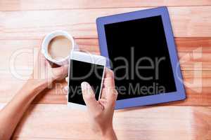 Businesswoman holding smartphone and coffee cup