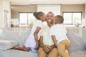 Happy father is kissed by his two children
