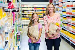 Smiling mother and daughter with grocery bags