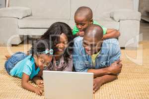 Happy family lying on the floor using laptop